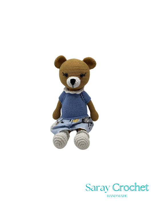 Crocheted teddy bear wearing a blue shirt and denim shorts on a white background with 'Saray Crochet' branding.