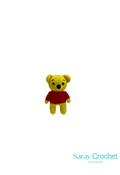 A small yellow and red plush toy designed to look like a bear with a round body and a red shirt, presented against a white background with the text 'Saray Crochet' at the bottom.