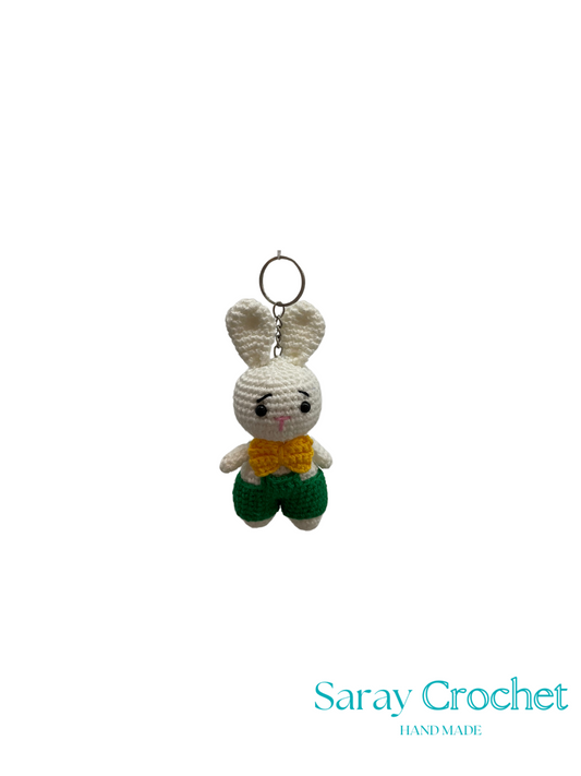 Crocheted bunny keychain with a yellow sweater on a white background, branded 'Saray Crochet'.