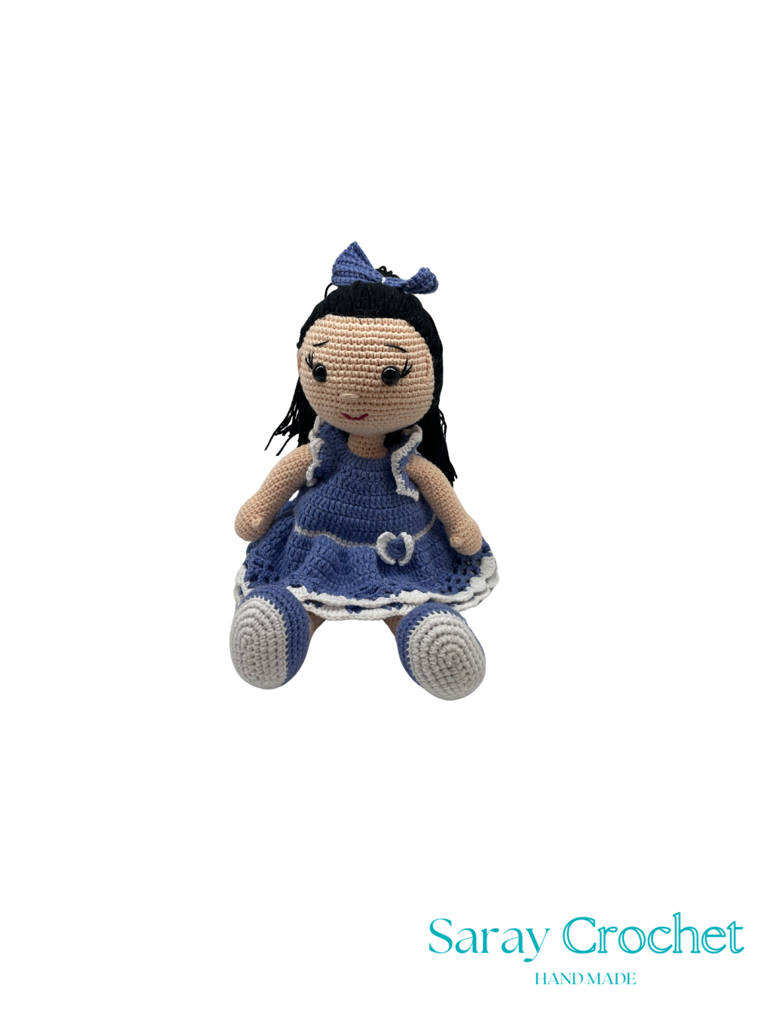 Crocheted doll with blue dress and black hair on a white background, branded 'Saray Crochet'.