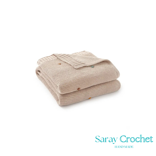 Folded beige knitted blanket with 'Saray Crochet' branding on a white background