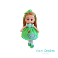 Handmade doll with light green dress, featuring a hand-embroidered snail motif, and a matching green bow in her hair.