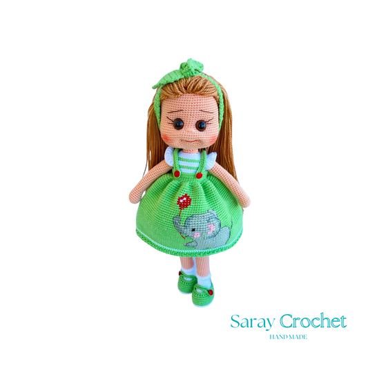 Handmade doll with light green dress, featuring a hand-embroidered snail motif, and a matching green bow in her hair.