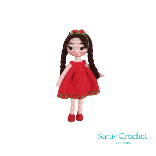 A handcrafted doll with a red dress and matching red shoes, featuring a green hairband with a bow.
