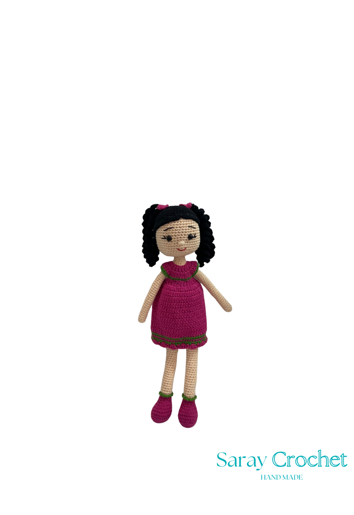 Handmade doll in a pink dress with black hair on a white background, branded 'Saray Crochet'.